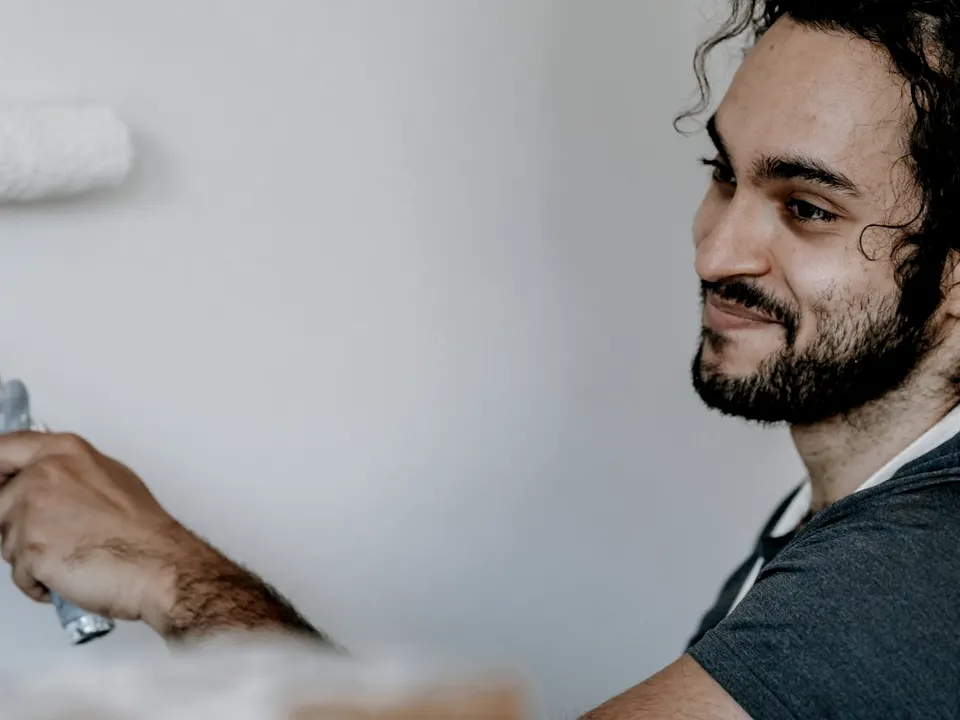 A painter rolling white paint onto an interior wall